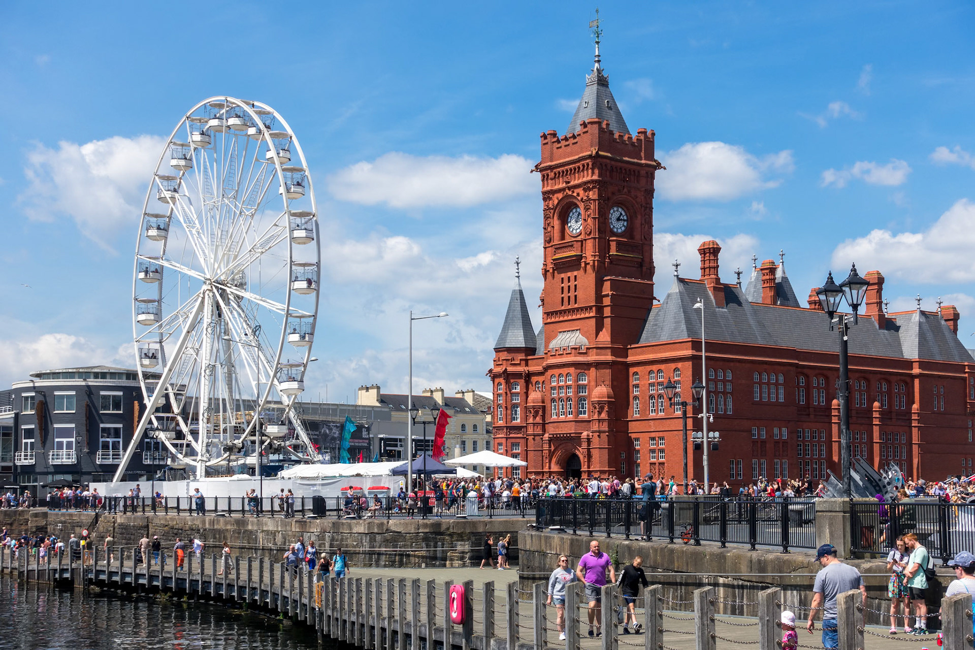 CARDIFF/UK - JULY 7 : View of the Ferris wheel and the Pierhead Building in Cardiff on July 7, 2019. Unidentified people
